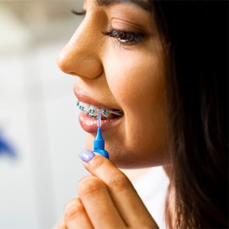 A girl with braces brushing her teeth