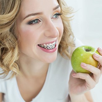 A woman with braces eating an apple