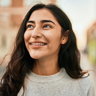 Closeup of girl with traditional braces smiling outside