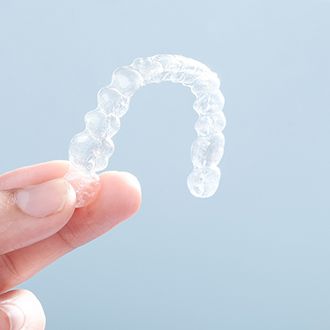 Patient holding an Invisalign tray in Milton