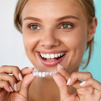 Smiling woman placing an Invisalign tray