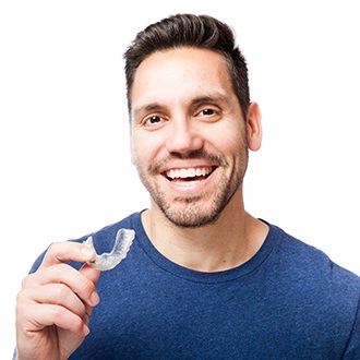 Smiling man holding an Invisalign tray