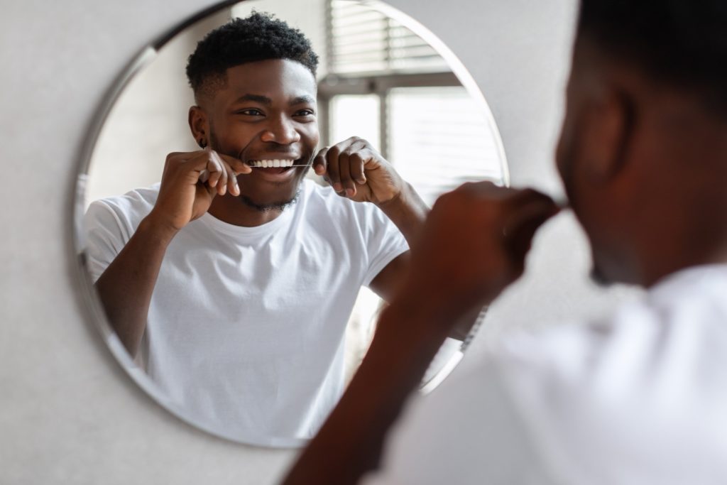 Man flossing in bathroom mirror