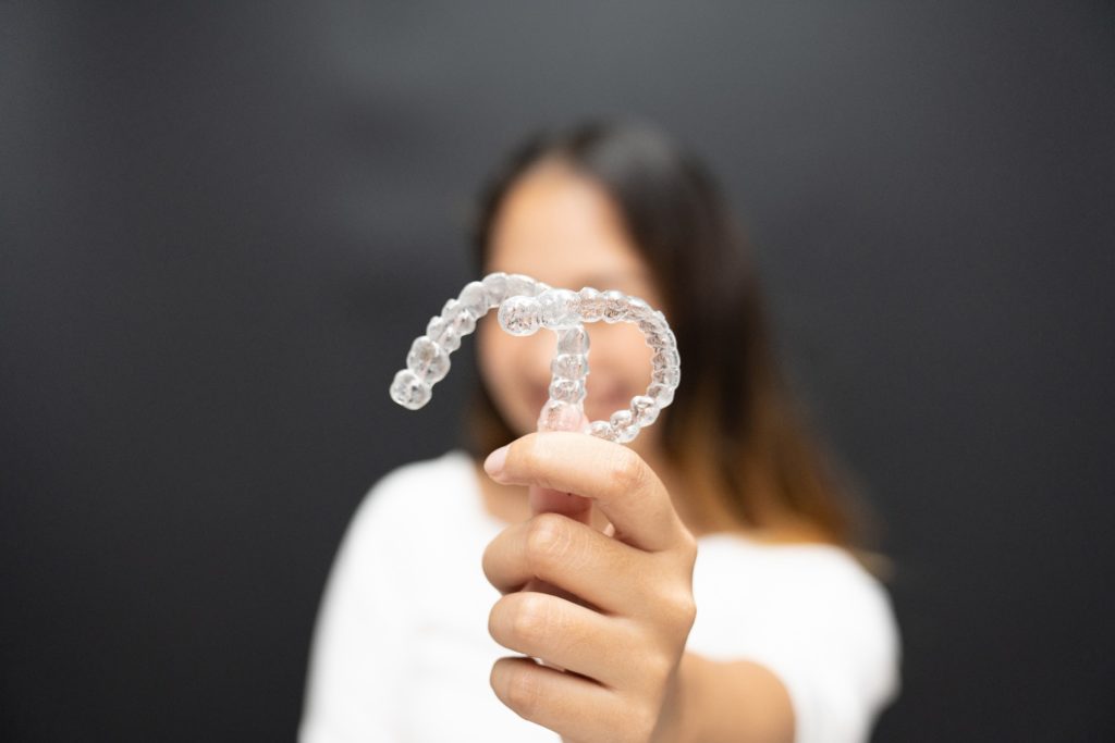 Closeup of clear retainers being held by patient