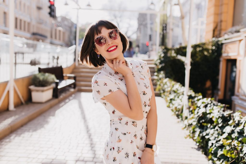 Woman in floral dress smiling outside