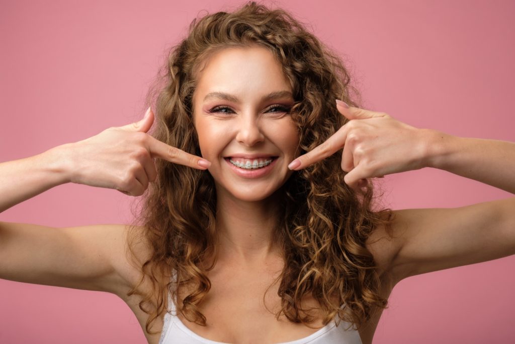 Woman smiling while pointing to her braces