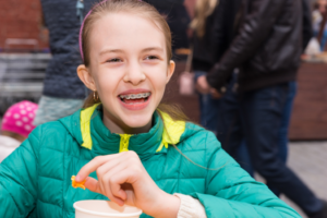 a child with braces smiling during lunch